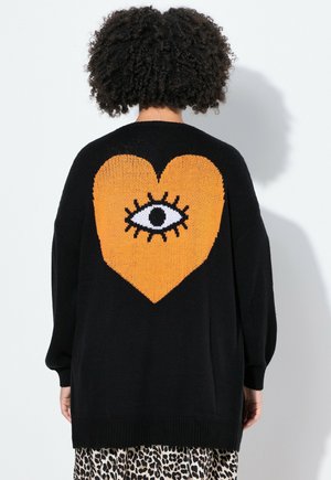 Zwarte gebreide cardigan met een oranje hart met een oogontwerp op de achterkant. Gestructureerd materiaal met lange mouwen en verlaagde schouders.