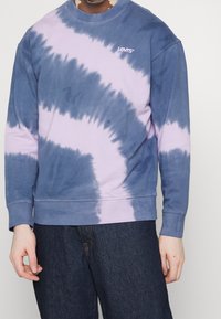 Felpa tie-dye Levi's in blu e lavanda, con colletto a girocollo, maniche lunghe e logo lavanda sul petto. Tessuto in cotone, morbida texture.