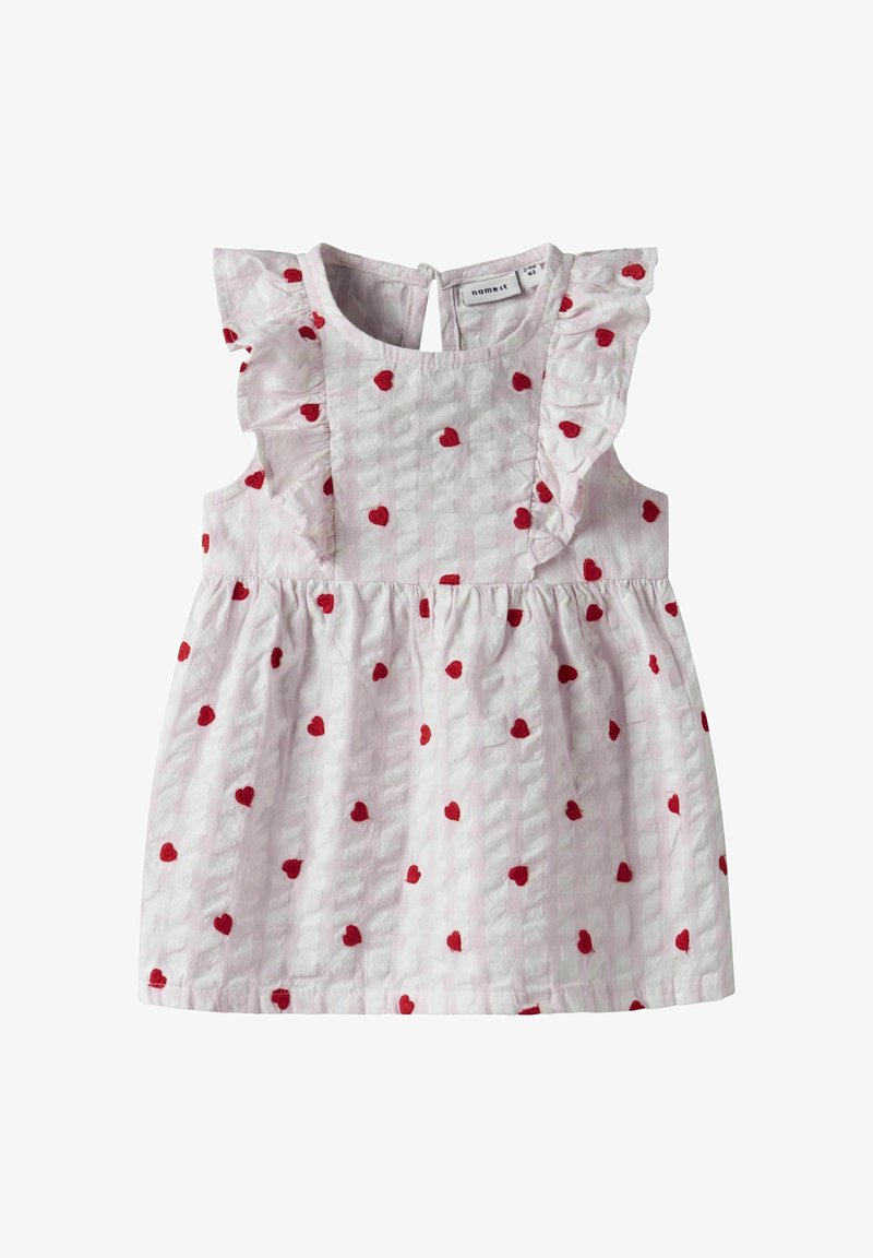 Svijetloružičasta haljina bez rukava s volanima na ramenima, koja ima cjeloviti uzorak crvenih srca i teksturiranu tkaninu. Zaključavanje na dugmad na leđima.