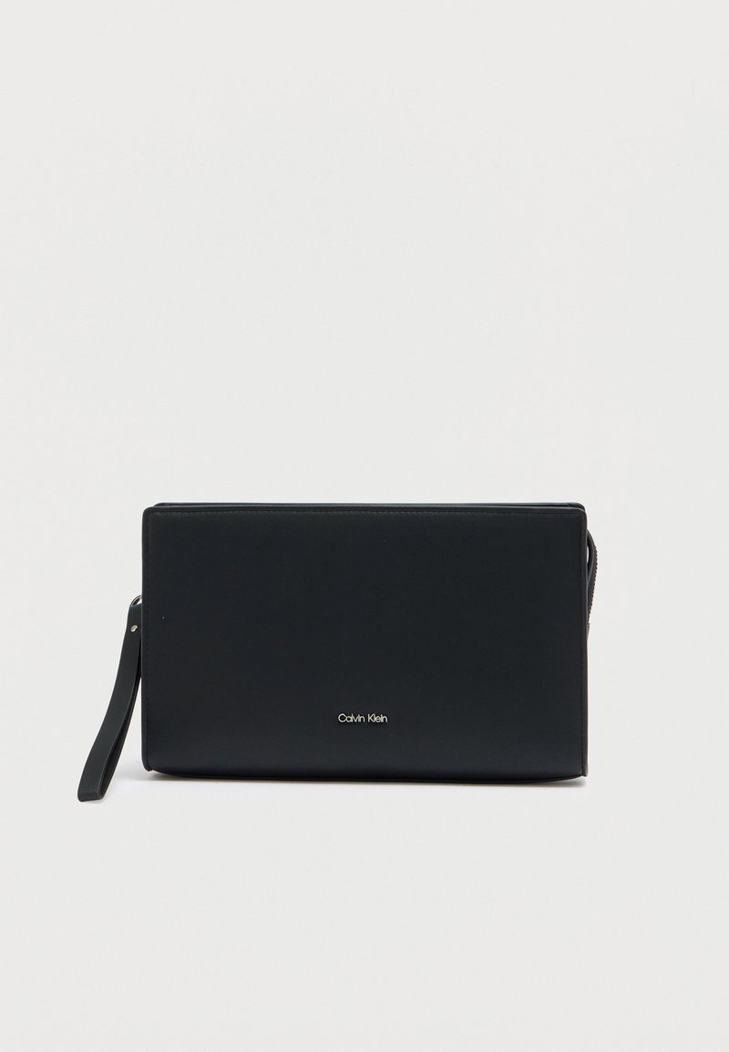 Pochette en cuir noir à texture lisse, fermeture éclair et bandoulière amovible. Présente un logo doré à l'avant.