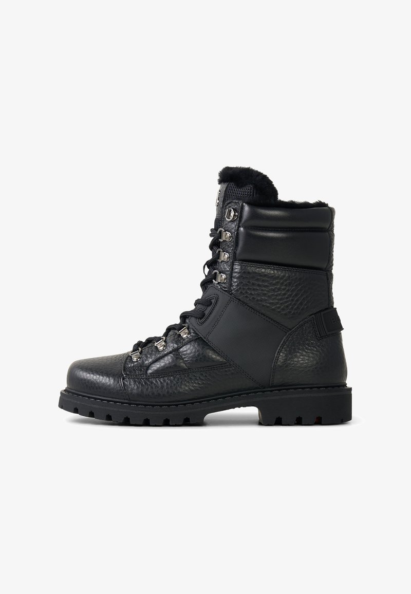 Schwarze Leder-Wanderschuhe mit gepolstertem Kragen, Metallösen und strukturierter Oberfläche sowie einer profilierten Sohle für besseren Grip.