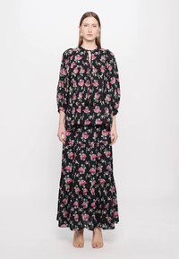 Svart blomstrete to-delt antrekk bestående av en bluse med ballongsler og et lagdelt maxiskjørt, prydet med rosa rosemønster.