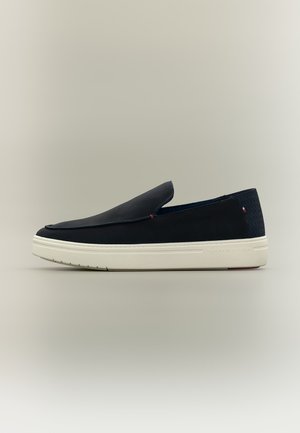 Dunkelblauer Slip-On-Sneaker mit weißer Gummisohle und dezentem Tommy Hilfiger-Logo an Ferse und Seite.