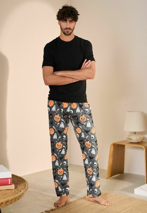 Black short-sleeve shirt paired with gray pants featuring orange pumpkins, ghosts, black cats, and skulls in a playful pattern.