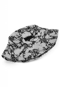 Buckethatt i tyg med ett svart och vitt abstrakt mönster. Har en bred skärm och en texturerad svart etikett framtill.