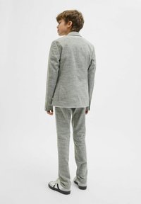 Grå, texturerad kostym med skräddarsydd passform, som har en ensidig kavaj och matchande byxor. Kombinera med vita och svarta sneakers.