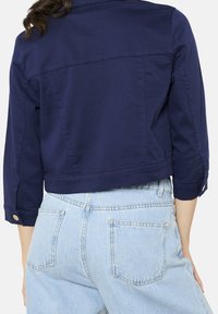 Granatowa krótka kurtka z mieszanki bawełny, z rękawami do łokcia, guzikiem zdobiącym mankiety oraz gładką, jednolitą teksturą.