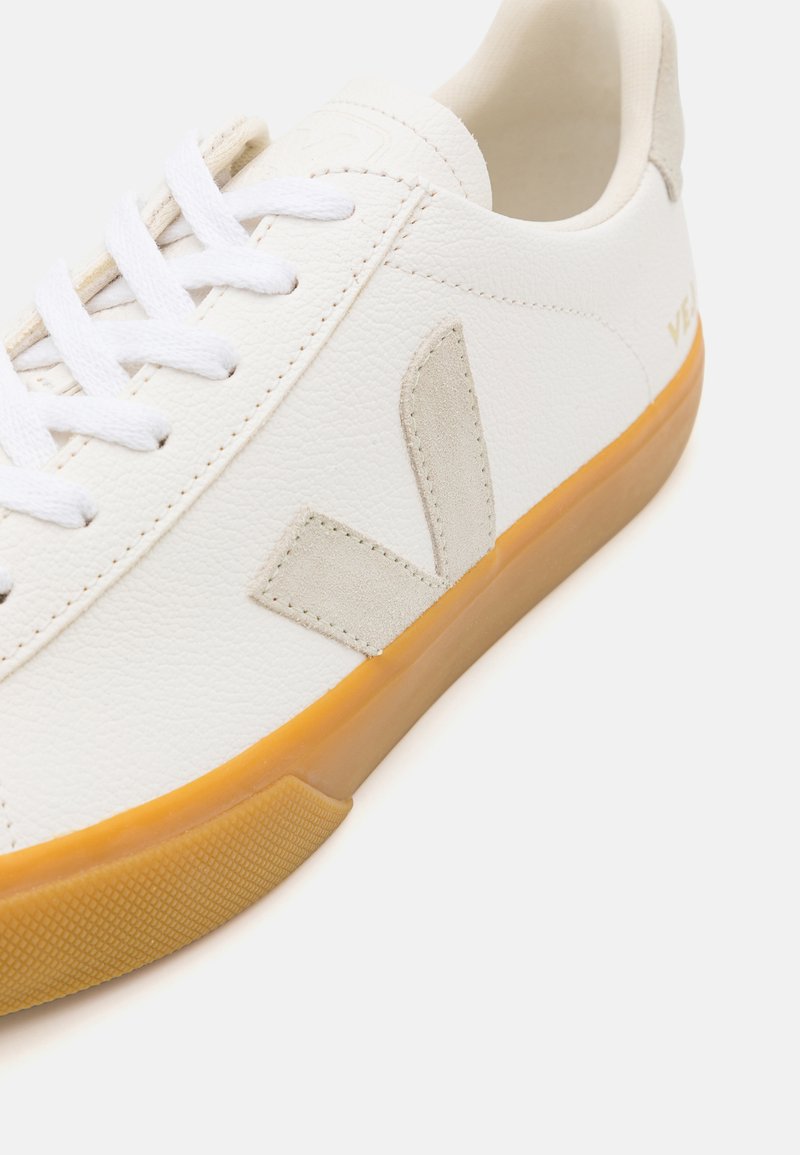 Baskets en cuir blanc avec un logo en suede beige et une semelle en gomme texturée. Équipées de lacets blancs et d'une doublure intérieure lisse.