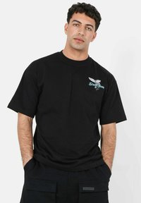 Zwarte katoenen t-shirt met een ronde hals, korte mouwen en een grafisch ontwerp met een adelaar en de tekst "Sixth June" op de borst.