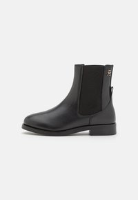 Botte de cheville en cuir noir avec panneaux latéraux élastiques, bout arrondi et petit talon bloc. Présente un détail de logo subtil près du haut.