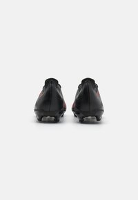 Black football boots with a streamlined design, featuring a textured upper, red accents, and molded studs for grip on the sole.