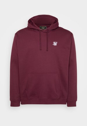 Burgundijska dukserica s kapuljačom napravljena od mekog materijala, s prednjim džepom i malim bijelim logotipom na prsima. Dugi rukavi i rebraste manžete.