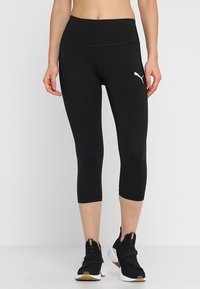 Černé capri legíny vyrobené z hladkého, elastického materiálu, s vysokým pasem a malým bílým logem Puma na levé straně.