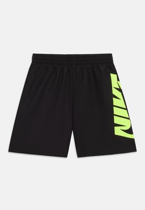 Shorts de sport noirs avec ceinture élastique et grand logo vertical "NIKE" jaune néon sur la jambe droite sur fond blanc.