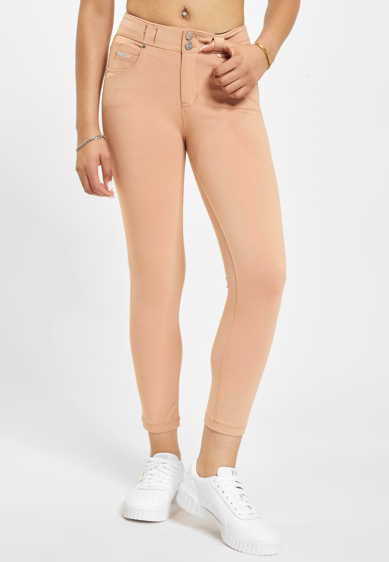 Peskegule leggings laget av elastisk materiale, med høy midje, slim fit og en frontlomme med knappeåpning.