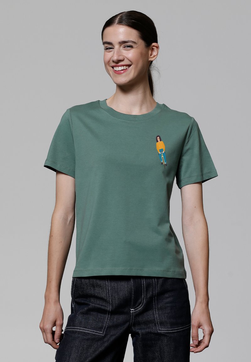 Groene katoenen t-shirt met een ronde hals en korte mouwen, voorzien van een kleine, kleurrijke grafiek van een persoon op de voorkant.