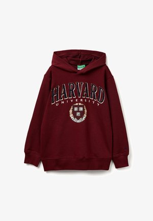 Sudadera con capucha color burdeos que presenta "HARVARD UNIVERSITY" en letras gruesas, con un emblema circular y el texto "VERITAS". Está hecha de una tela suave.