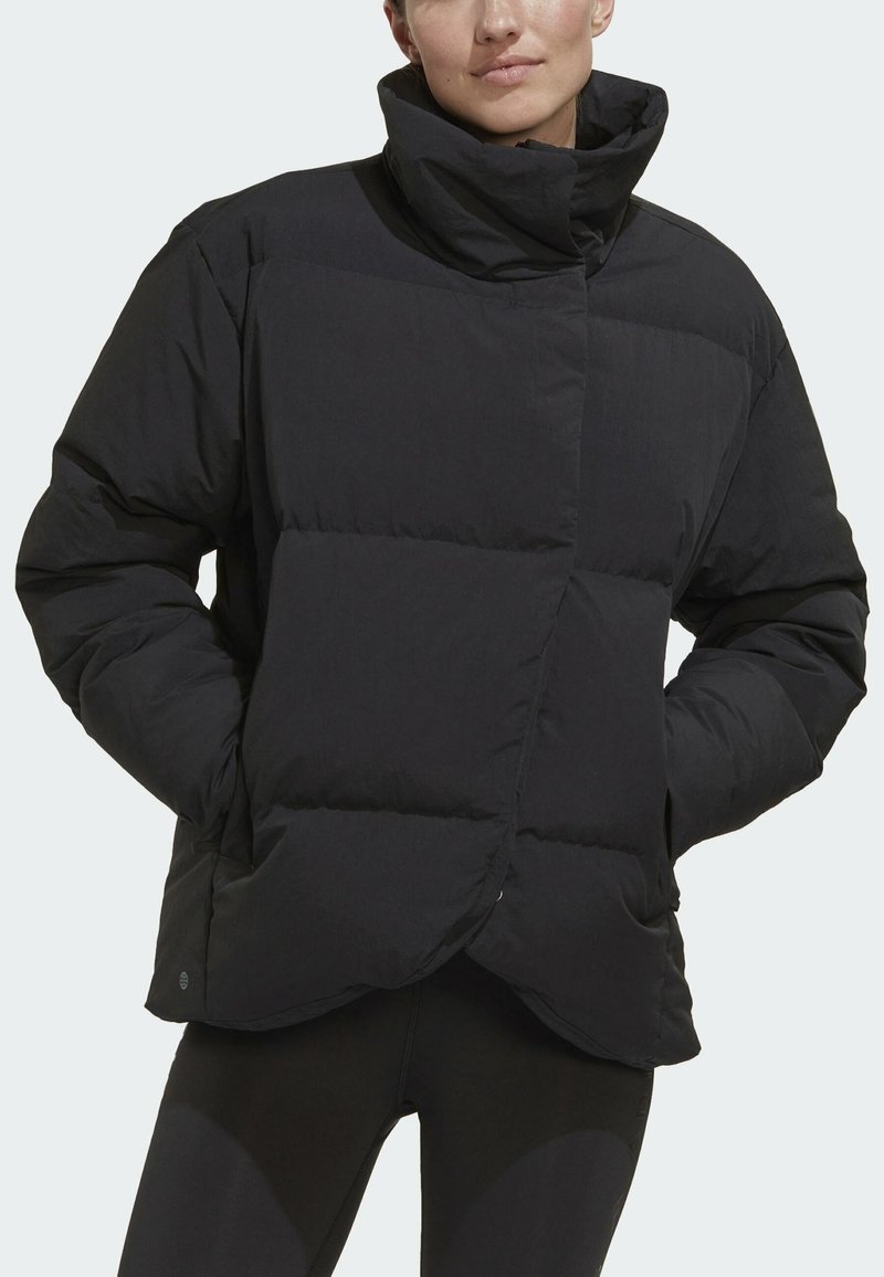Schwarze Puffjacke mit hohem Kragen, gestepptem Design und lockerer Passform. Das Material erscheint glatt mit einem matten Finish.