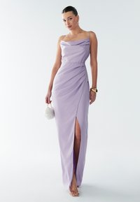 Lilla õhtukleit spagetiribadega, drapeeritud korsett, küljsõlmega ja sileda tekstuuriga. Sobib valge clutchi ja pahkluu-rihmaga kontsakingadega.