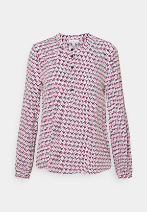 Blouse blanche à manches longues avec un motif géométrique rouge, noir et gris sur toute la surface, et des boutons noirs sur le devant.