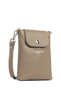 Sac bandoulière en cuir marron avec un rabat, fermoir à pression en argent, logo embossé, sangle ajustable et finition lisse.