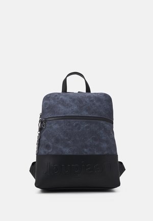 Ciemnoniebieski i czarny plecak z przednią kieszenią na zamek i wytłoczonym logo marki na dolnej części, na prostym jasnym tle.