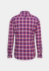 Camisa de cuadros con patrones en rojo, azul y blanco; cuello abotonado; mangas largas; y puños con botones. Vista trasera mostrada.