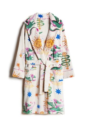 Personne nouant la ceinture d'un peignoir en polaire blanc avec des motifs colorés de soleil, étoile et abstraits.