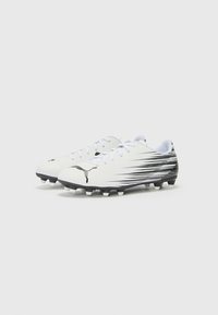 Crampons de football blancs avec des accents graphiques noirs, design épuré, tige texturée et crampons moulés pour une meilleure traction. Lacets conçus pour un maintien sécurisé.