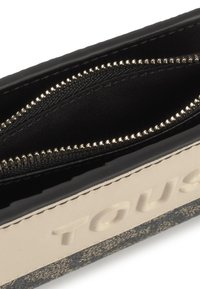 Czarny i kremowy portfel o teksturowanym wykończeniu, z zamkiem błyskawicznym, wewnętrznymi przegrodami i wytłoczonym logo marki.
