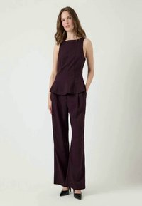 Top peplum burdeos con rayas y pantalones de pierna ancha a juego, ambos con una textura suave y un ajuste entallado. Tacones negros completan el conjunto.