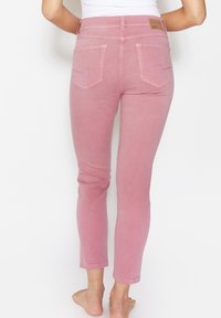 Růžové denimové džíny se slim fit střihem, zadními kapsami se švy a viditelnou koženou nášivkou značky na pase.