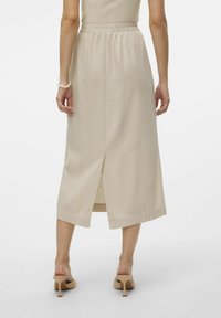 Beige Rock mittlerer Länge mit Rückenschlitz, elastischem Bund und geradem Schnitt. Glatter, leichter Stoff mit feiner Textur.