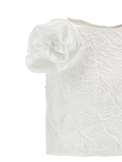 Hvid tekstureret ærmeløs top med en stor lagdelt stofblomsterdetalje på venstre skulder.