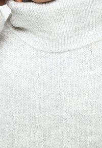 Maglione a collo alto grigio chiaro realizzato in un morbido tessuto testurizzato con un design a coste, caratterizzato da un colletto alto e una silhouette aderente.