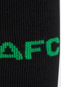Calcetín negro hecho de material acanalado, con la inscripción verde "AFC" destacada en un lado.