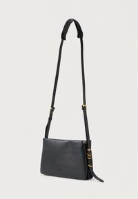 Černá kožená crossbody taška s nastavitelným popruhem, hladkým povrchem, obdélníkovým tvarem, zlatými kovovými akcenty a minimalistickým designem.