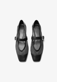 Ballerine nere con una tomaia in rete caratterizzata da un motivo a diamante. Punta quadrata con un tacco liscio nero a contrasto e una tracolla regolabile.
