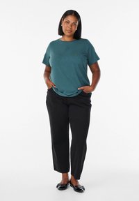 Teal kortärmad t-shirt med subtilt mönster, parat med svarta raka byxor och svarta lägenheter. Slät kvalitet, avslappnad passform.