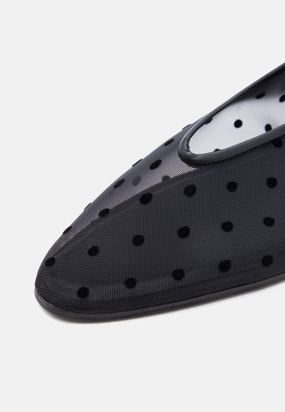 Μαύρο μυτερό παπούτσι με διαφανές δίχτυ και μαύρα πουά, που δείχνει λεπτομερή υφή και λεία επένδυση γύρω από το άνοιγμα.