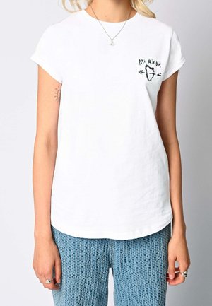 Person wearing a white T-shirt with "Mi Amor" and a heart design on the chest, paired with textured blue knitted pants.