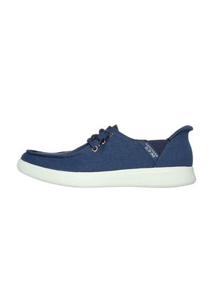 Zapato casual de tela azul marino con suela de goma blanca, puntera redonda y diseño de cordones. Presenta una pequeña etiqueta de la marca en el costado.