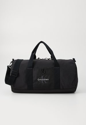 Zwarte duffelbag met stoffen buitenkant, dubbele handvatten, afneembare schouderband en opvallend Calvin Klein-logo. Minimalistisch ontwerp.
