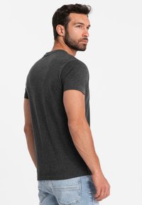 Kolgrå kortärmad T-shirt i bomullsblandning med rund halsringning och klassisk passform, kombinerad med ljusa tvättade denimjeans.