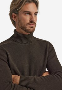 Dunkelbrauner, gerippter Rollkragenpullover mit tailliertem Design. Der Stoff wirkt weich mit einer glatten Textur und langen Ärmeln.