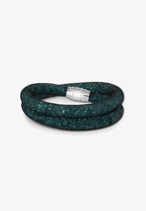 Bracelet tressé en maille vert foncé, avec un fermoir en argent brillant. La texture présente un motif en diamant, renforçant la profondeur visuelle.
