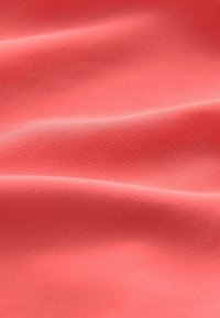 Korall színű szövet sima textúrával, lágy, redőzött ráncokkal, amelyek a rugalmasságot és az könnyű anyagot jelzik. Nincs látható mintázat vagy díszítés.