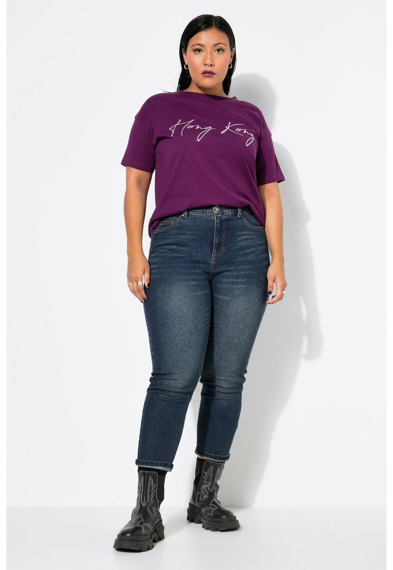 Camiseta de algodón morada con el texto "Hong Kong"; combinada con jeans skinny de color azul oscuro; botas negras por encima del tobillo con costuras decorativas.