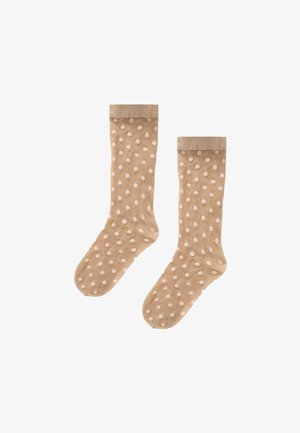 Chaussettes beiges transparentes avec de petits motifs floraux blancs et des bords doux, posées à plat côte à côte sur un fond blanc.
