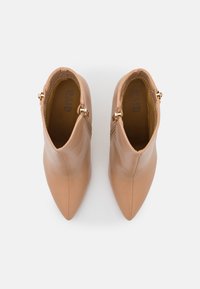 Helle Kunstleder-Ankle Boots mit spitzem Zehenbereich, seitlichen Reißverschlüssen und glatter Textur, ausgestattet mit goldenen Hardware-Details und einem eleganten Design.
